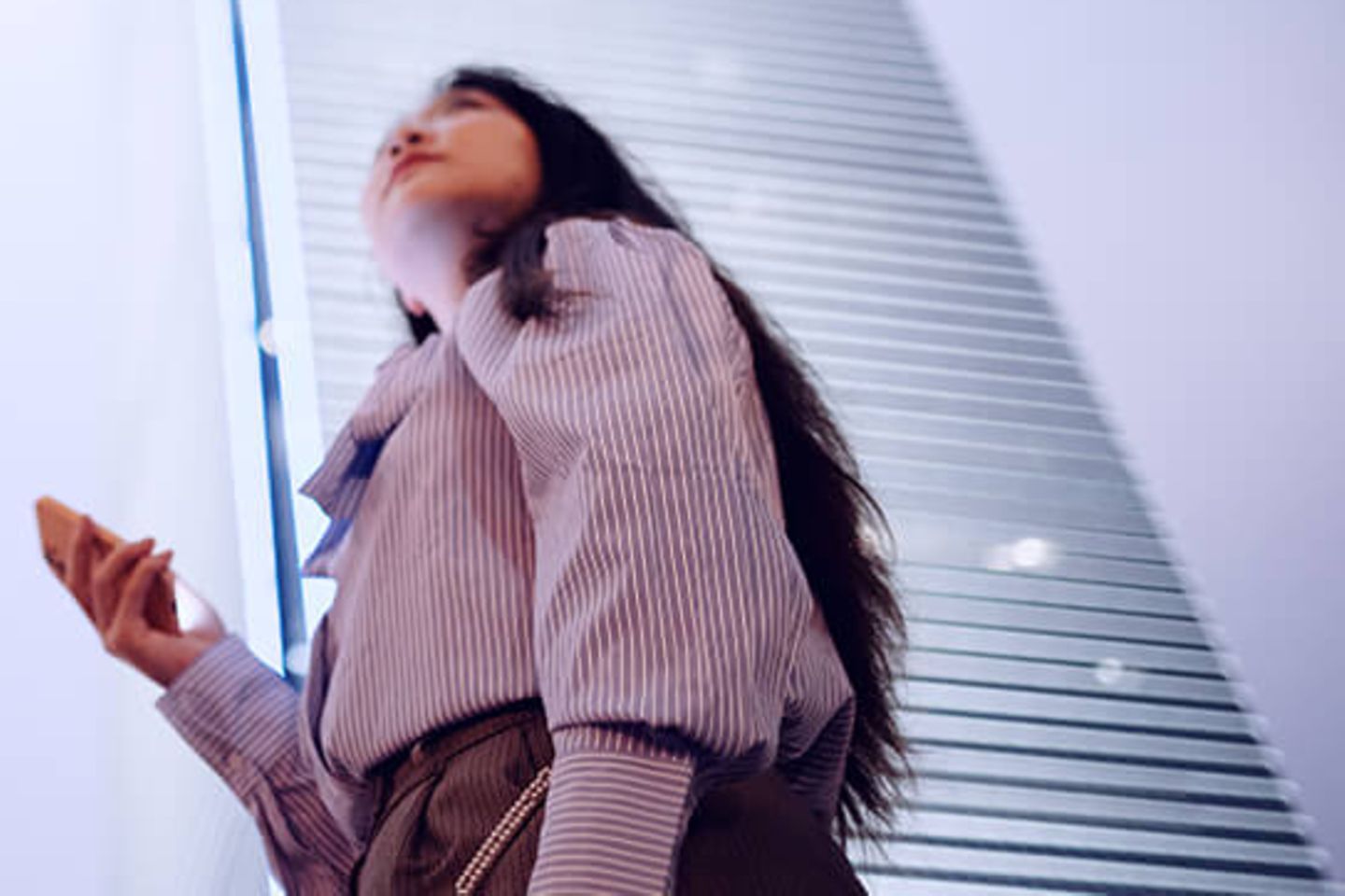 Woman with smartphone looking up to office skyscrapers