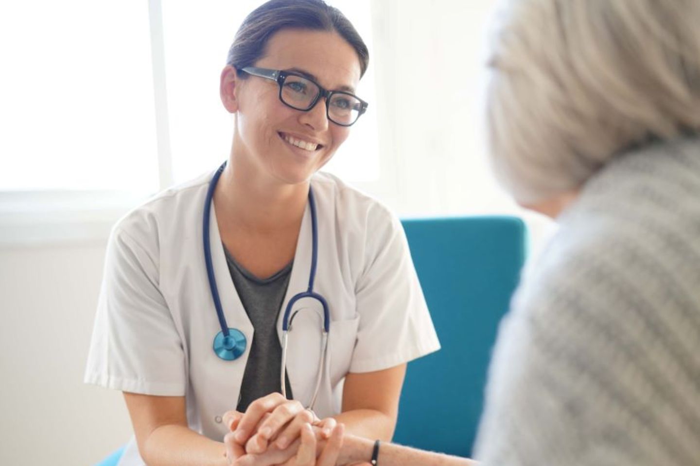 Lächelnde Ärztin, die einer älteren Patientin die Hand hält, native AWS-Services zur Verbesserung der Sicherheit