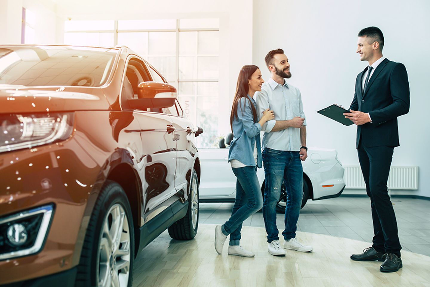 Een jong stel in een autodealer in gesprek met een verkoper.