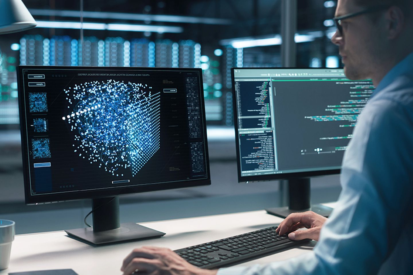 Un ingénieur en informatique est assis à un bureau devant un écran sur lequel s’affiche une quantité de données graphiques.