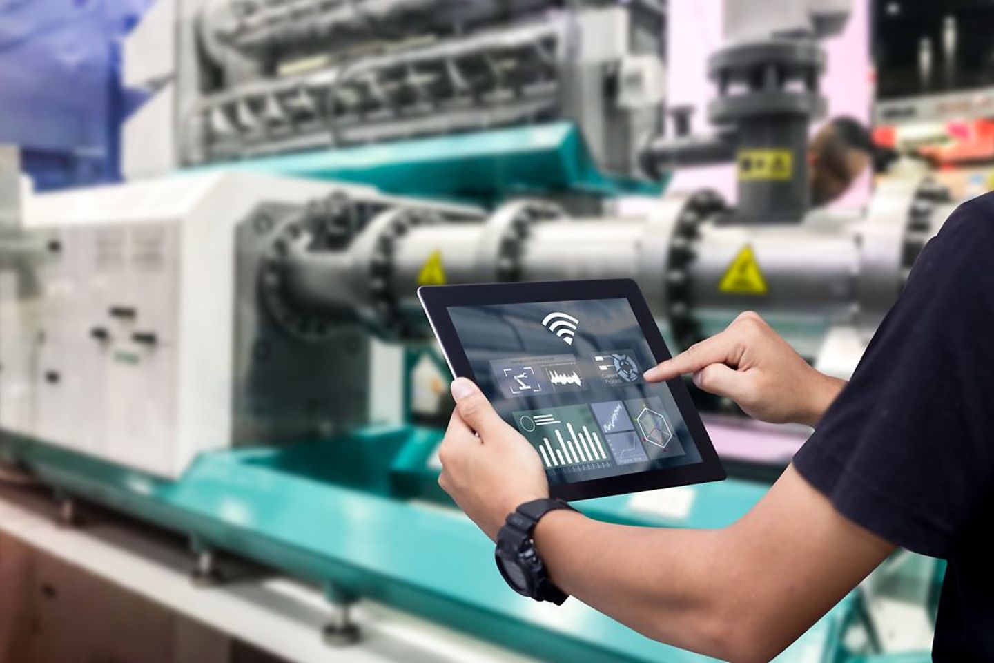 Manos sosteniendo la tableta en la máquina de automatización borrosa como fondo