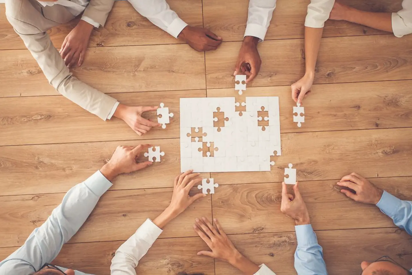 Parceiros de negócios jogando um quebra-cabeça feito de peças brancas