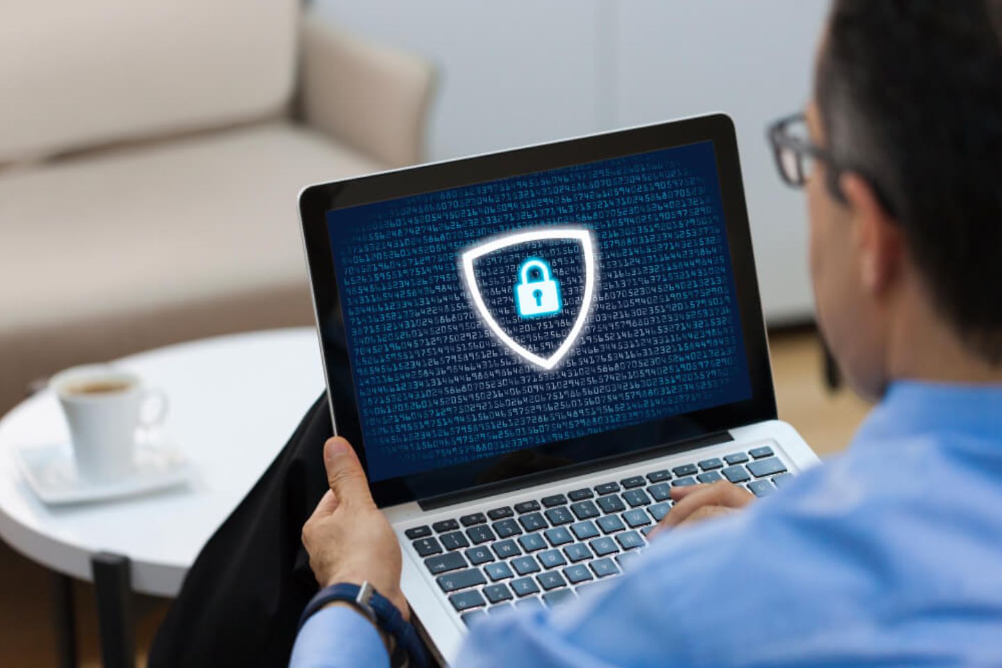 Mann mit Laptop, Datenschutz-Logo am Bildschirm.