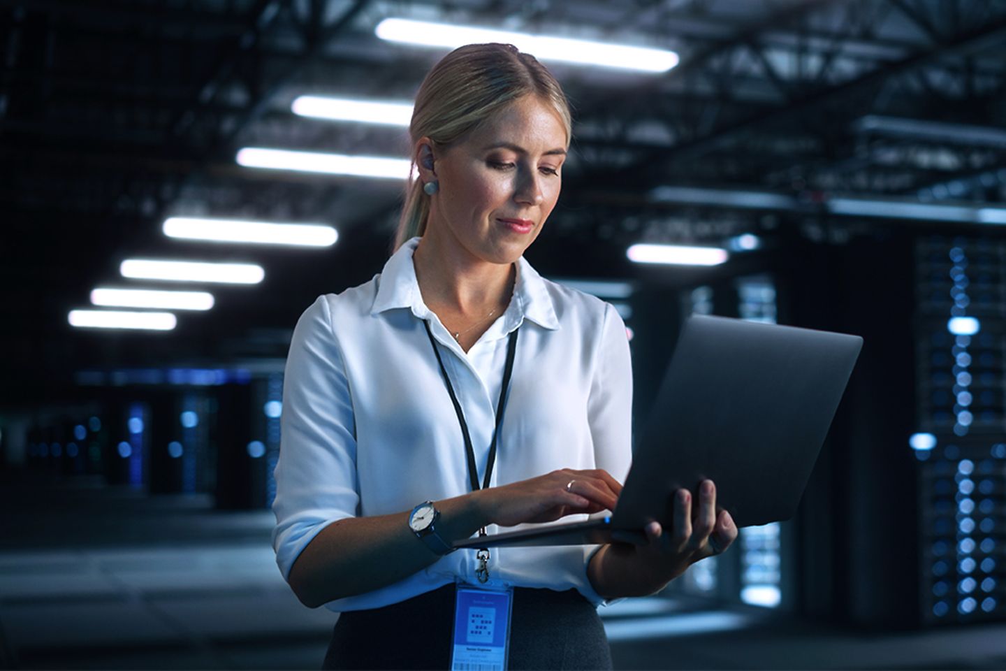 Une ingénieure utilise un ordinateur portable dans une installation de cloud computing d'une ferme de serveurs