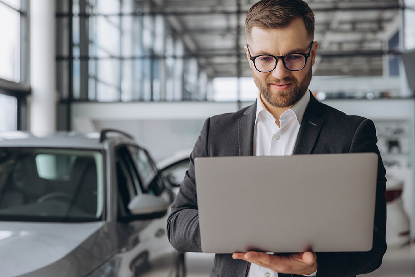 A car salesman with laptop in the car dealership