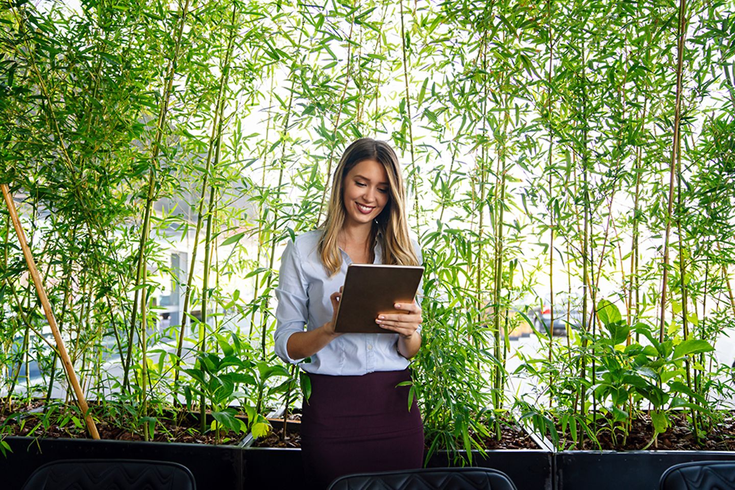 Woman checking data on tablet in front of green plants background