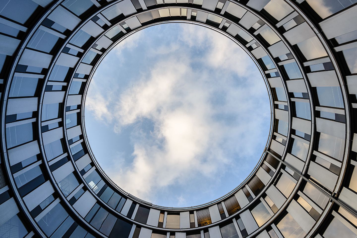 Wolken spiegeln sich in den Fenstern eines modernen Bürogebäudes