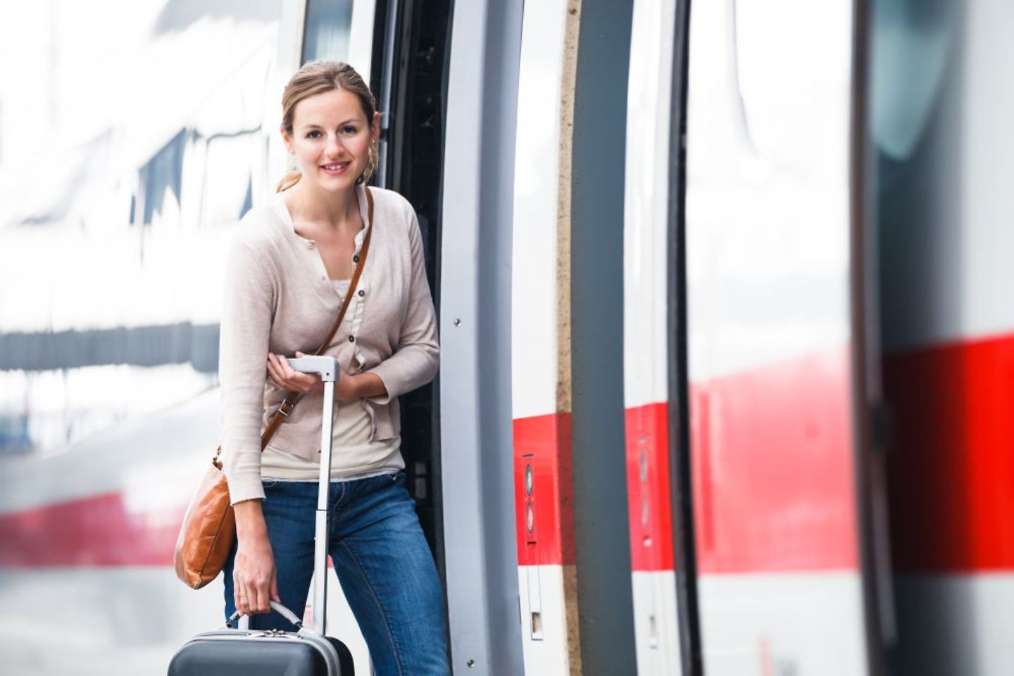 Frau mit Koffer vor einem Zug der Deutschen Bahn
