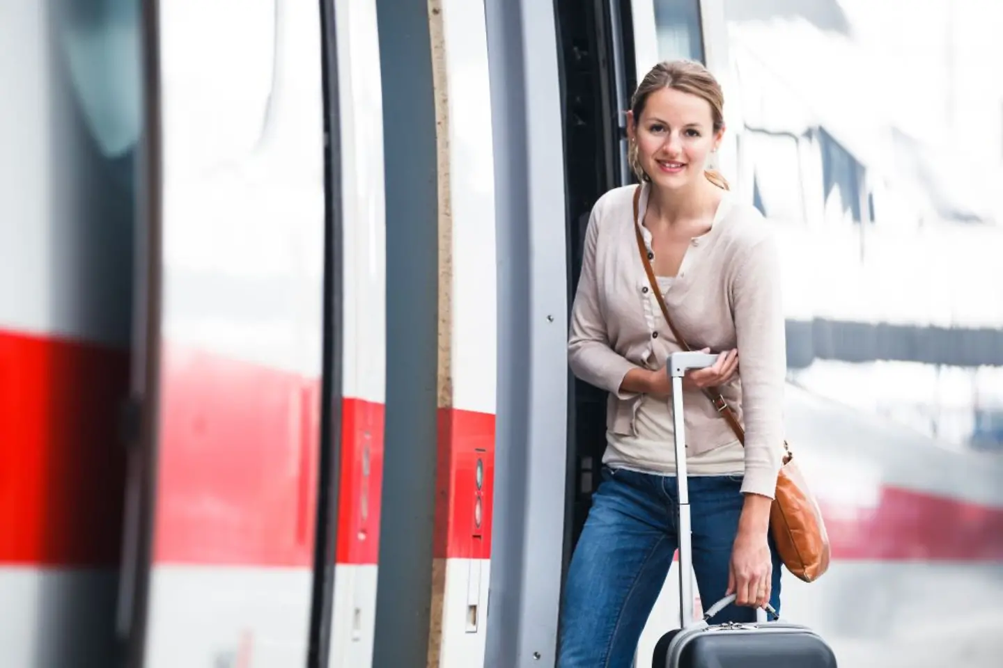 Mujer con maleta delante de un tren de Deutsche Bahn