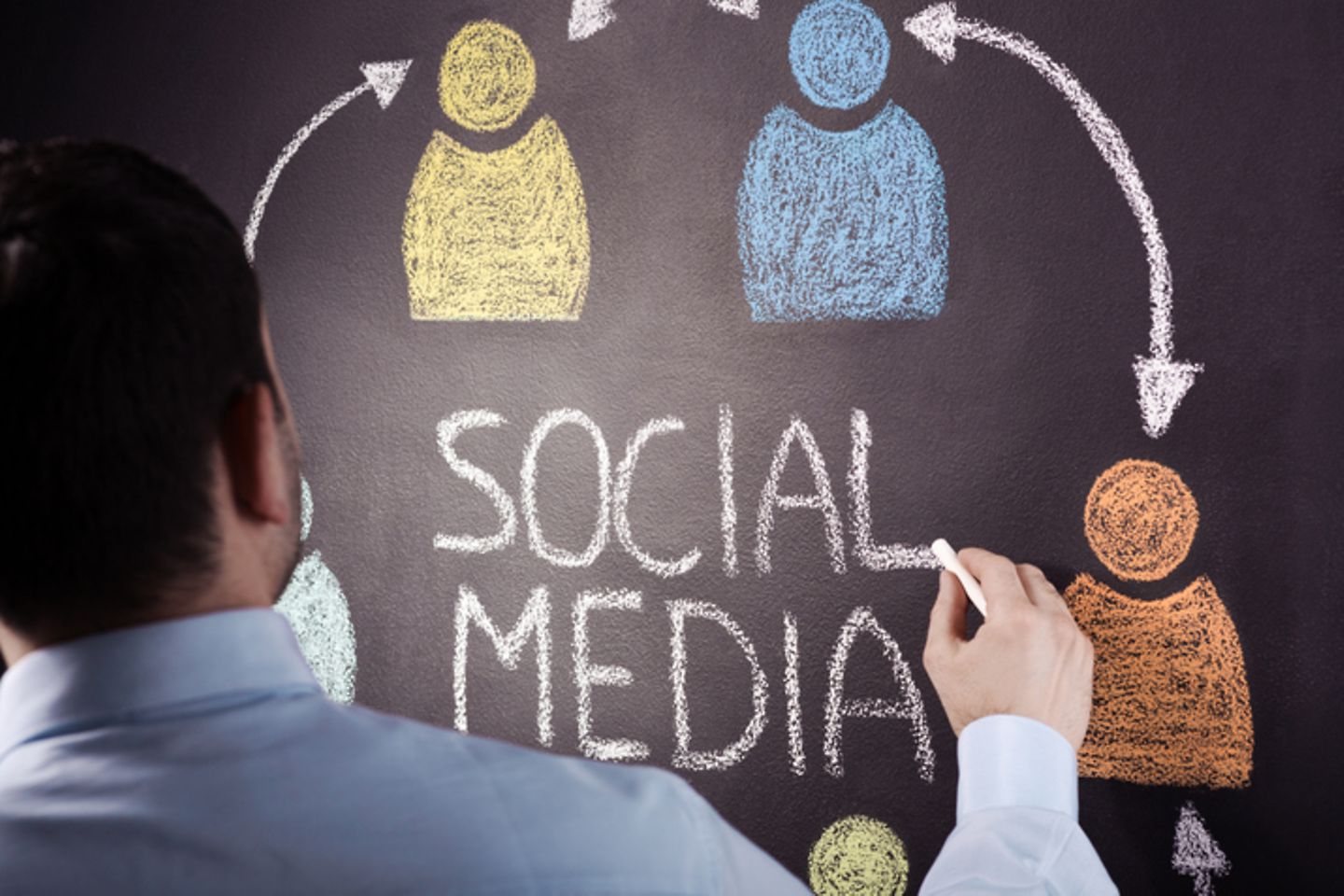 Man stands in front of blackboard and writes social media on chart.