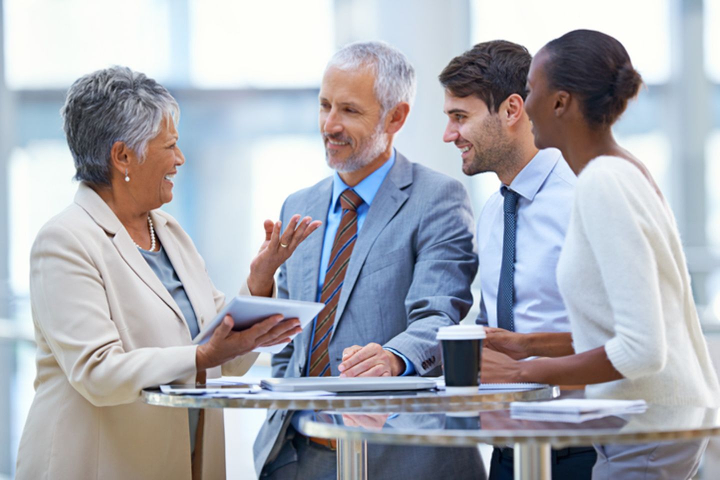 Four people in business attire converse at the bar table.