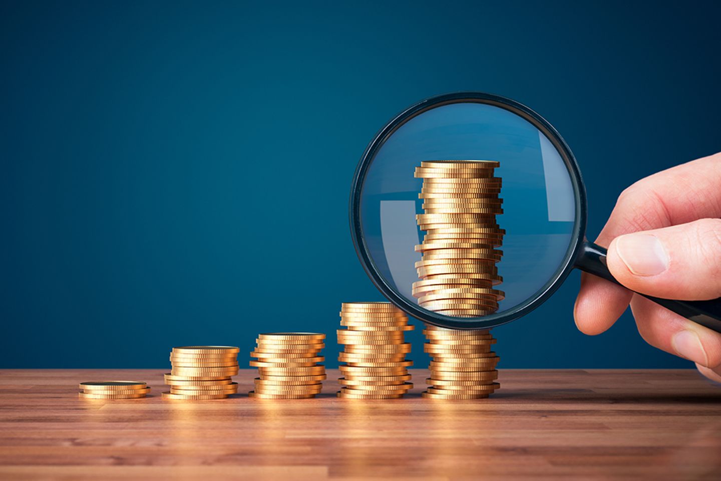 Pièces de monnaie empilées avec une loupe au premier plan