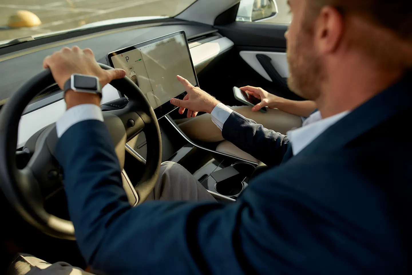 Young caucasian man touching on-board computer screen in his car.