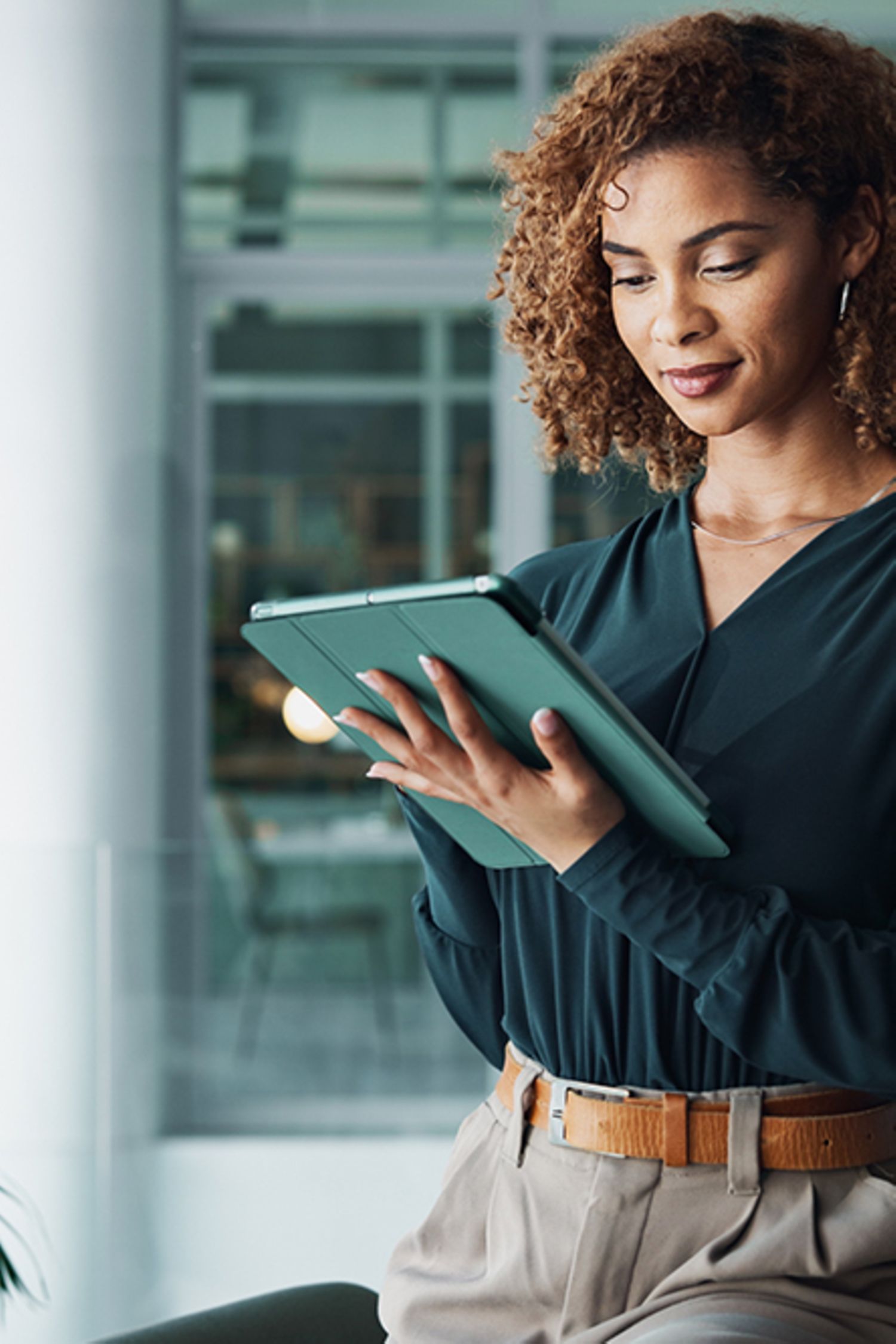 Female office worker in office accessing data on tablet