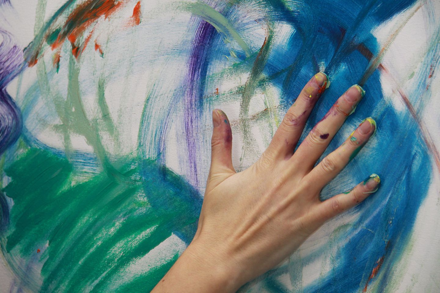 An artist paints with his hands on a canvas.