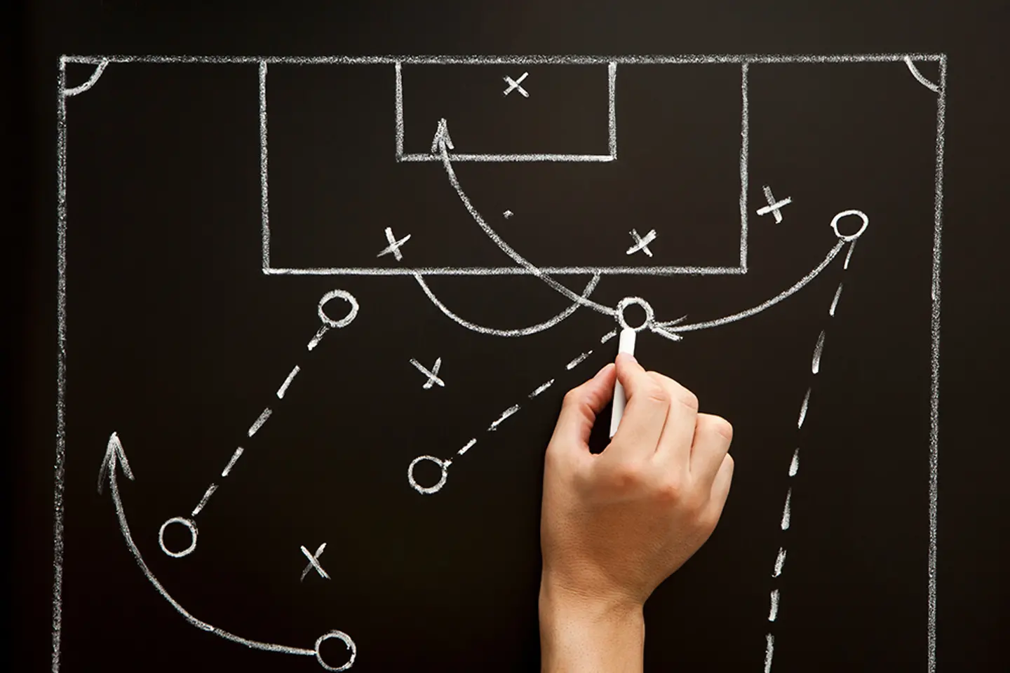 Un entrenador diseñando una estrategia para un partido de fútbol en el vestuario.
