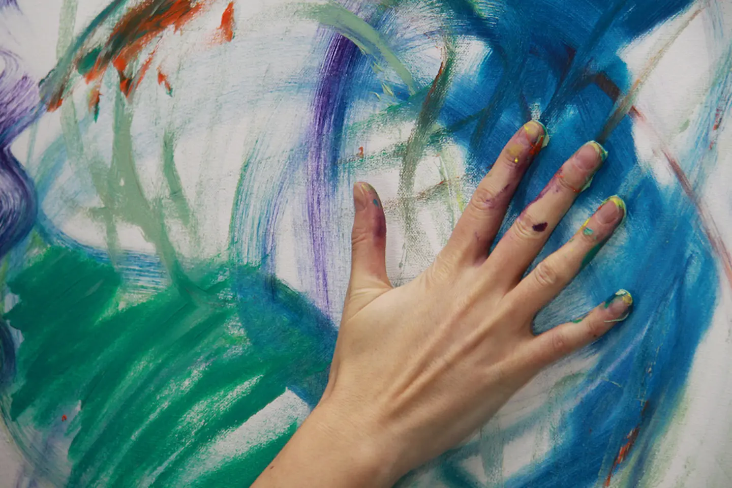 Een kunstenaar schildert met zijn handen op een doek.