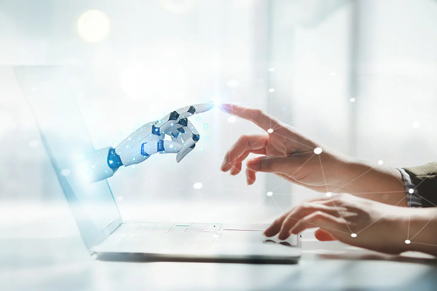 Eine menschliche und eine robotische Hand berühren sich vor einem Laptop-Bildschirm