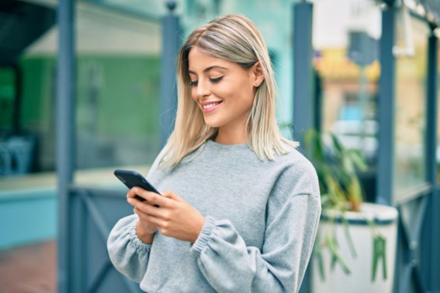 Lächelnde Bürgerin nutzt den Smart Chat der Öffentlichen Verwaltung auf ihrem Smartphone in der Stadt