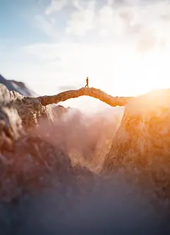Ein Mann läuft auf einer beeindruckenden Bergbrücke in die Sonne