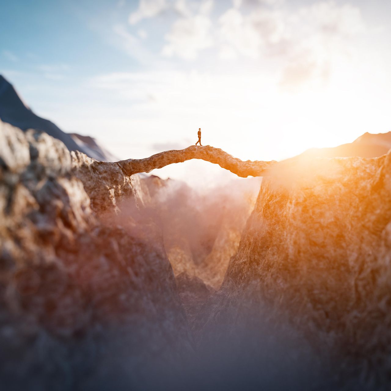 Man walking on an impressing mountain bridge into the sun