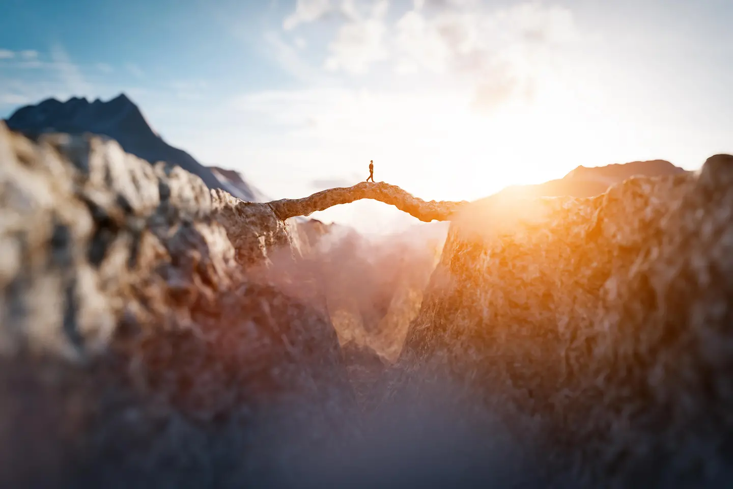 Man walking on an impressing mountain bridge into the sun
