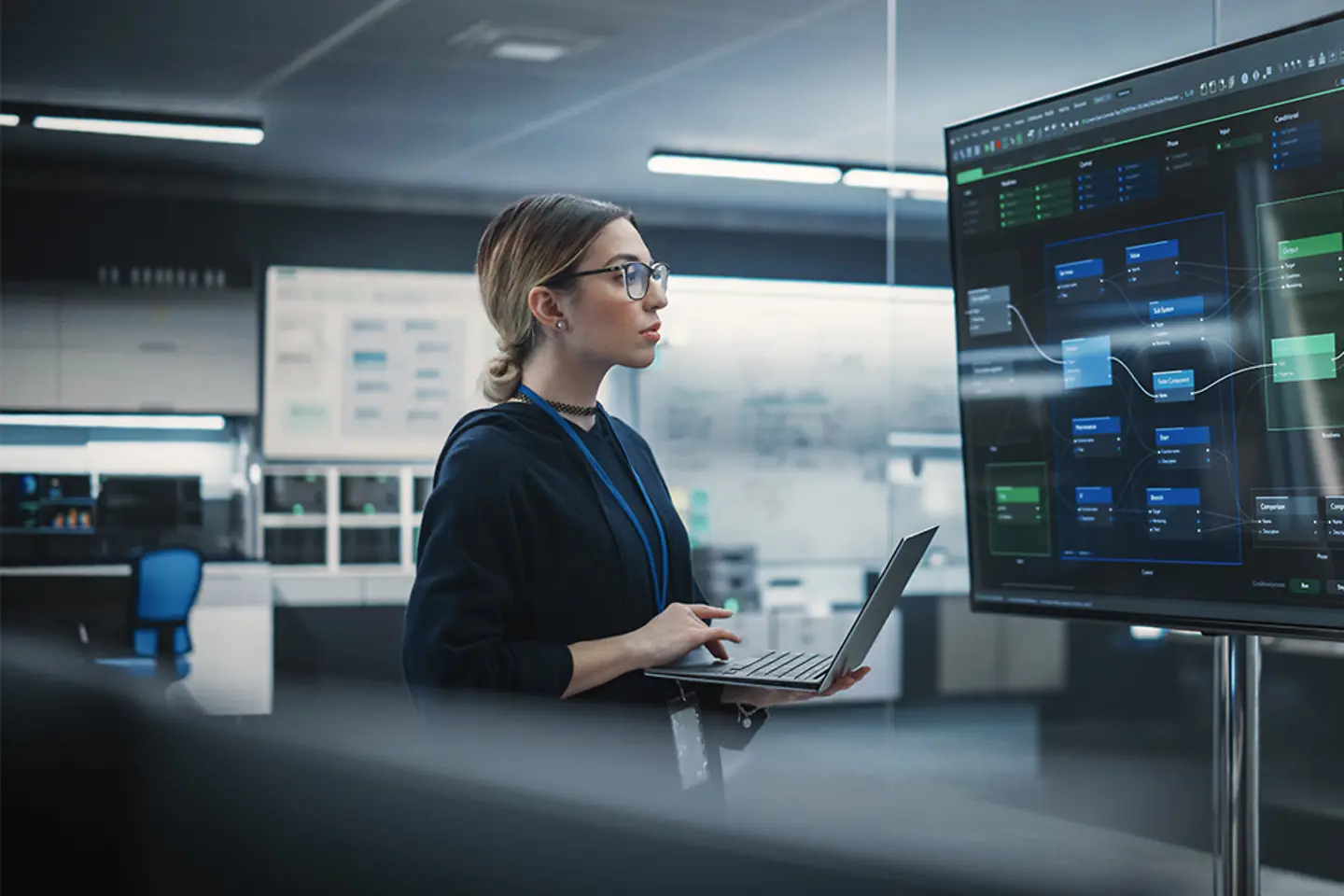 Een QA-engineer werkt op een laptop en controleert grote schermen.