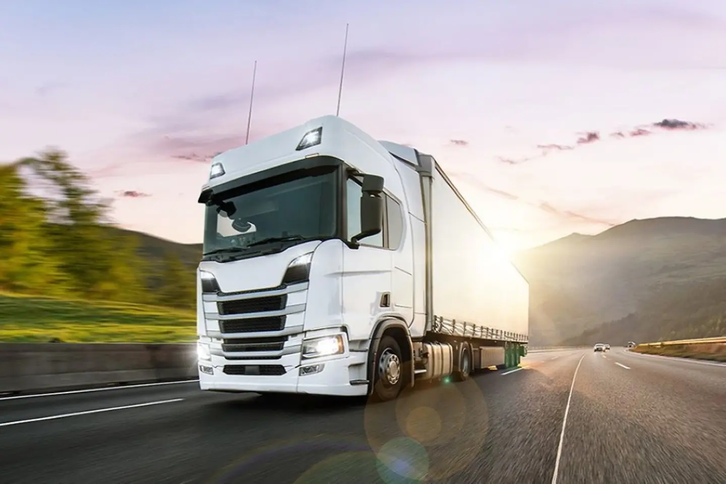 Weisser LKW fährt im Sonnenuntergang auf einer Autobahn