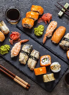 Sushi Rollen mit Reis, Fisch, Sojasauce auf einem dunklen steinernern Hintergrund