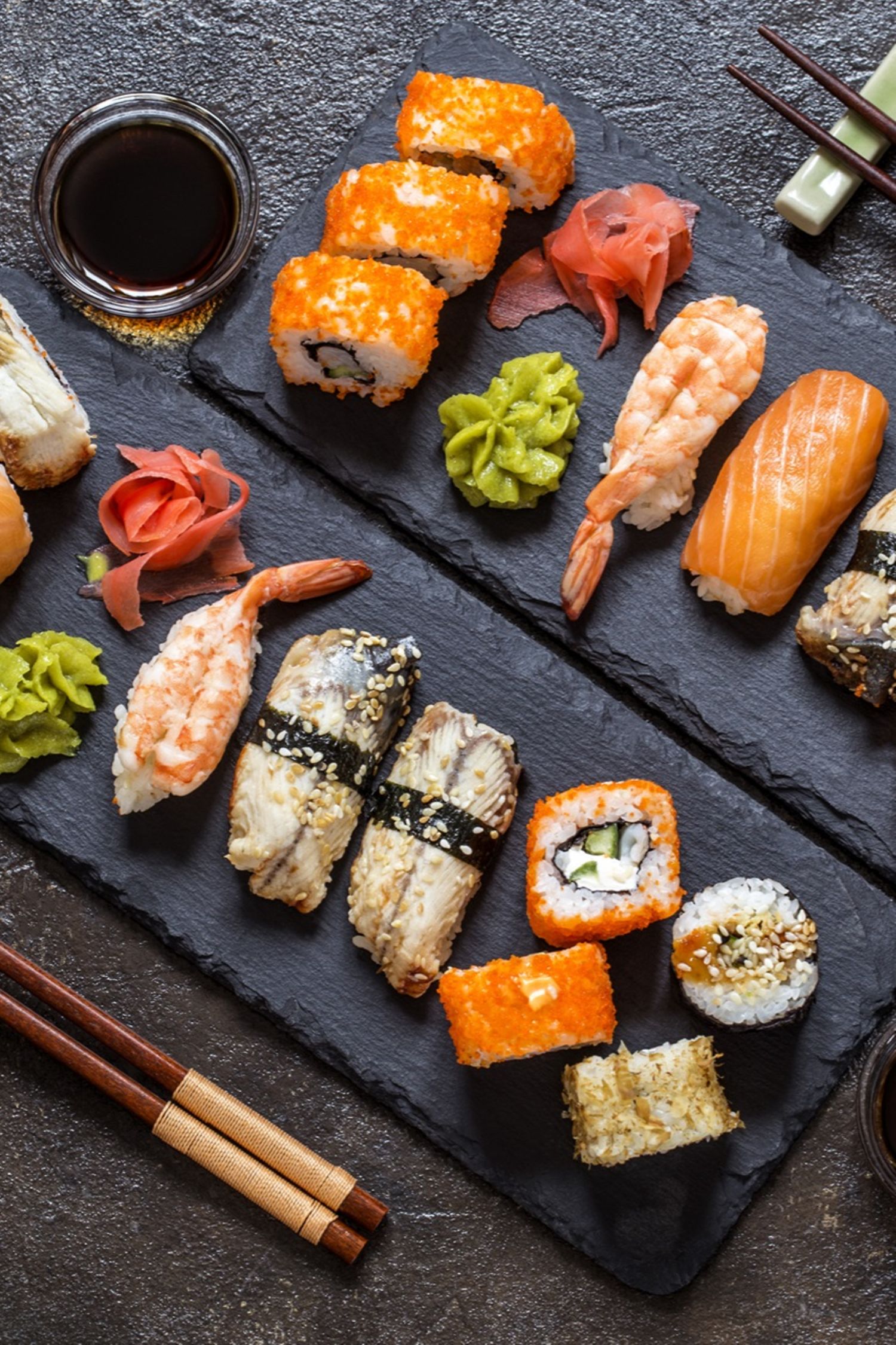 Sushi Rollen mit Reis, Fisch, Sojasauce auf einem dunklen steinernern Hintergrund