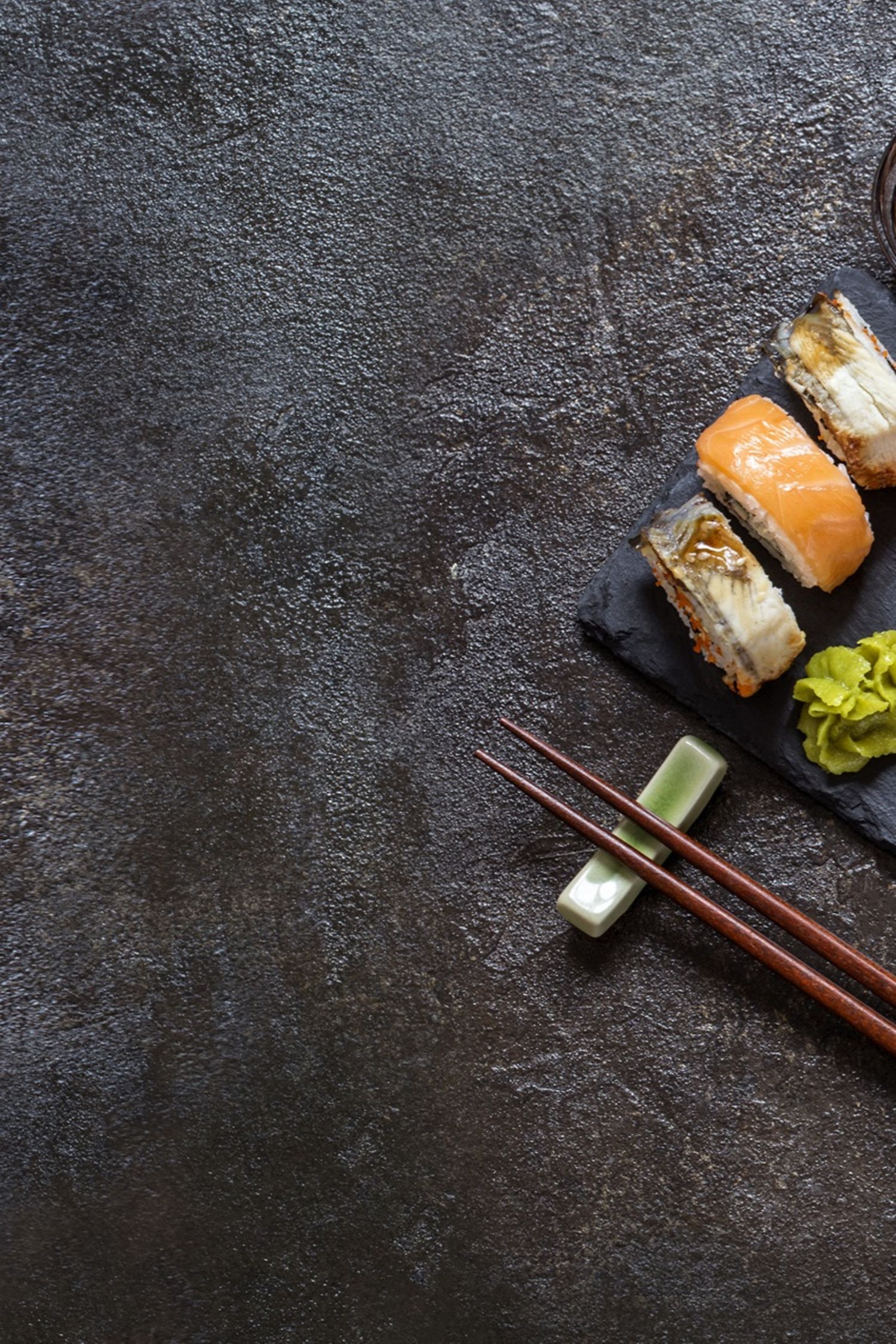Sushi Rollen mit Reis, Fisch, Sojasauce auf einem dunklen steinernern Hintergrund