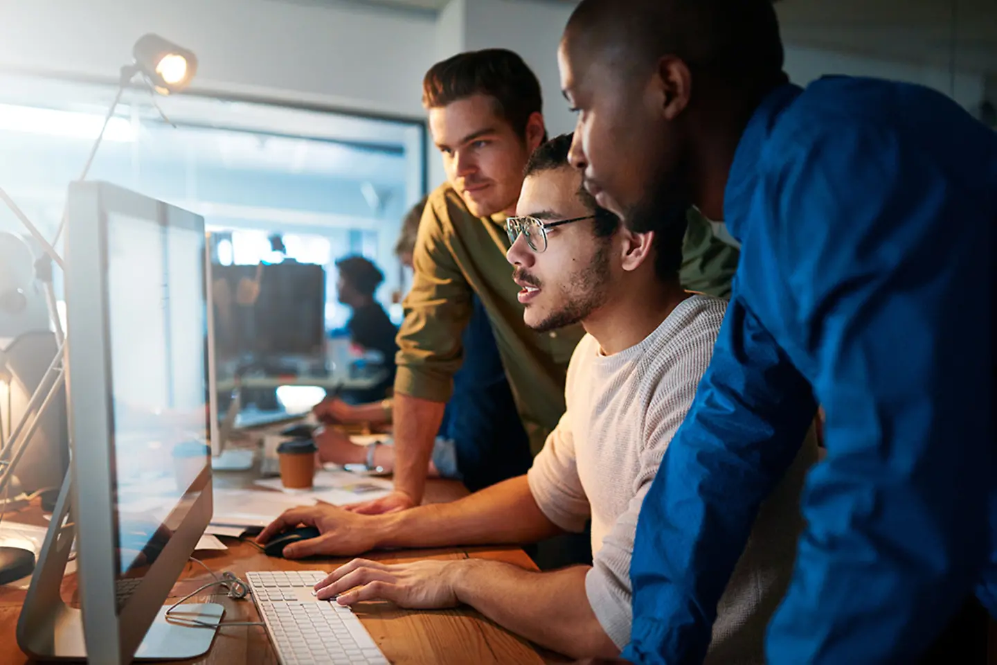 IT support team members gathered at a desktop.