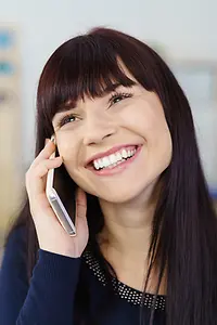 Lachende junge Frau beim Telefonieren mit ihrem Smartphone