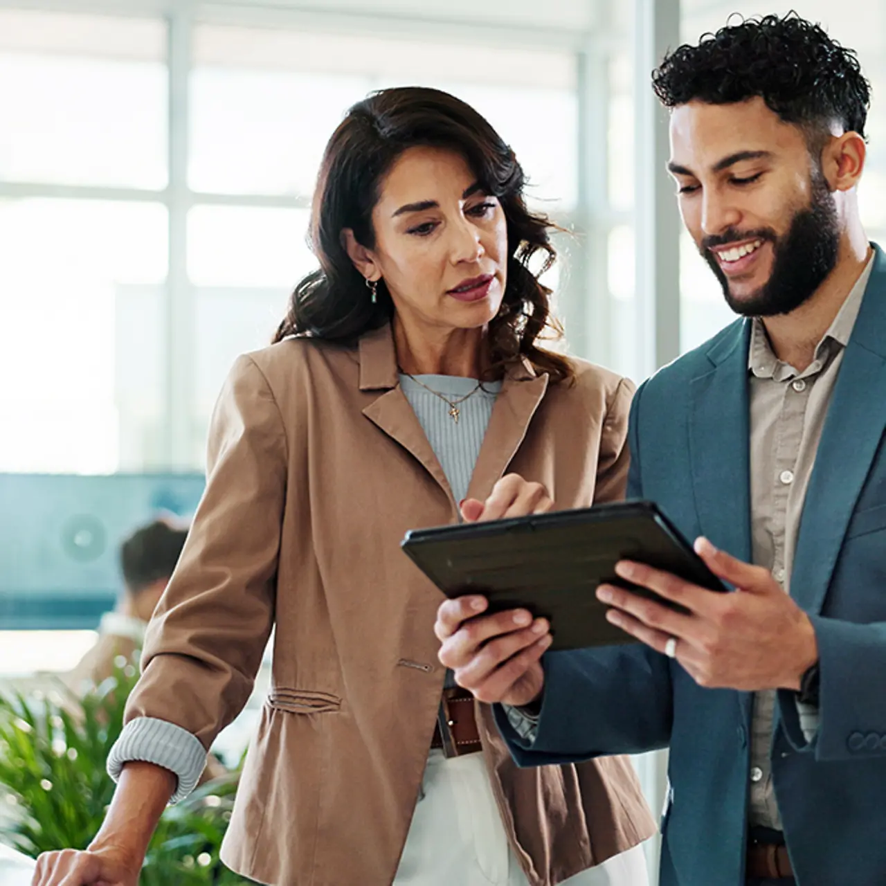 Two professionals discuss office work using a tablet as a reference.