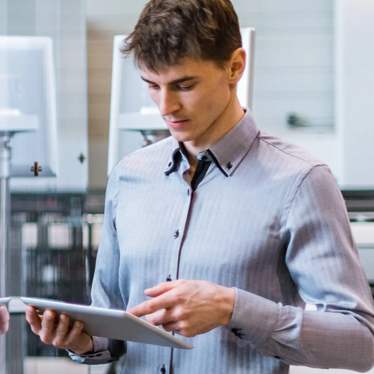 Hombre con una tablet delante de una cinta transportadora con brazo robotizado