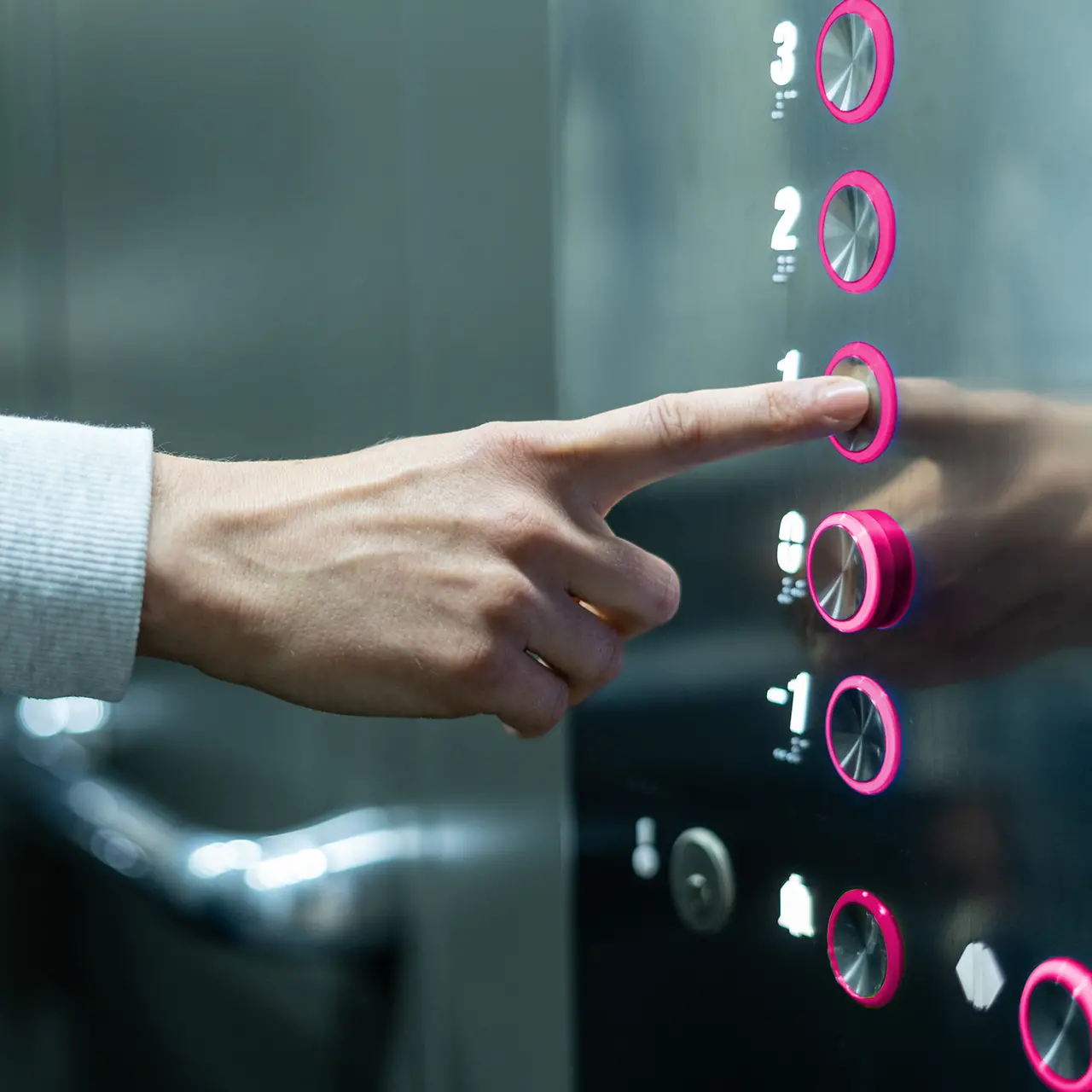 Person in an elevator pushing magenta button