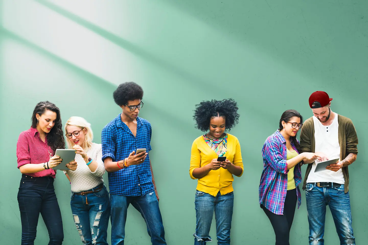 Een groep jongeren met tablets, mobiele telefoons en laptops