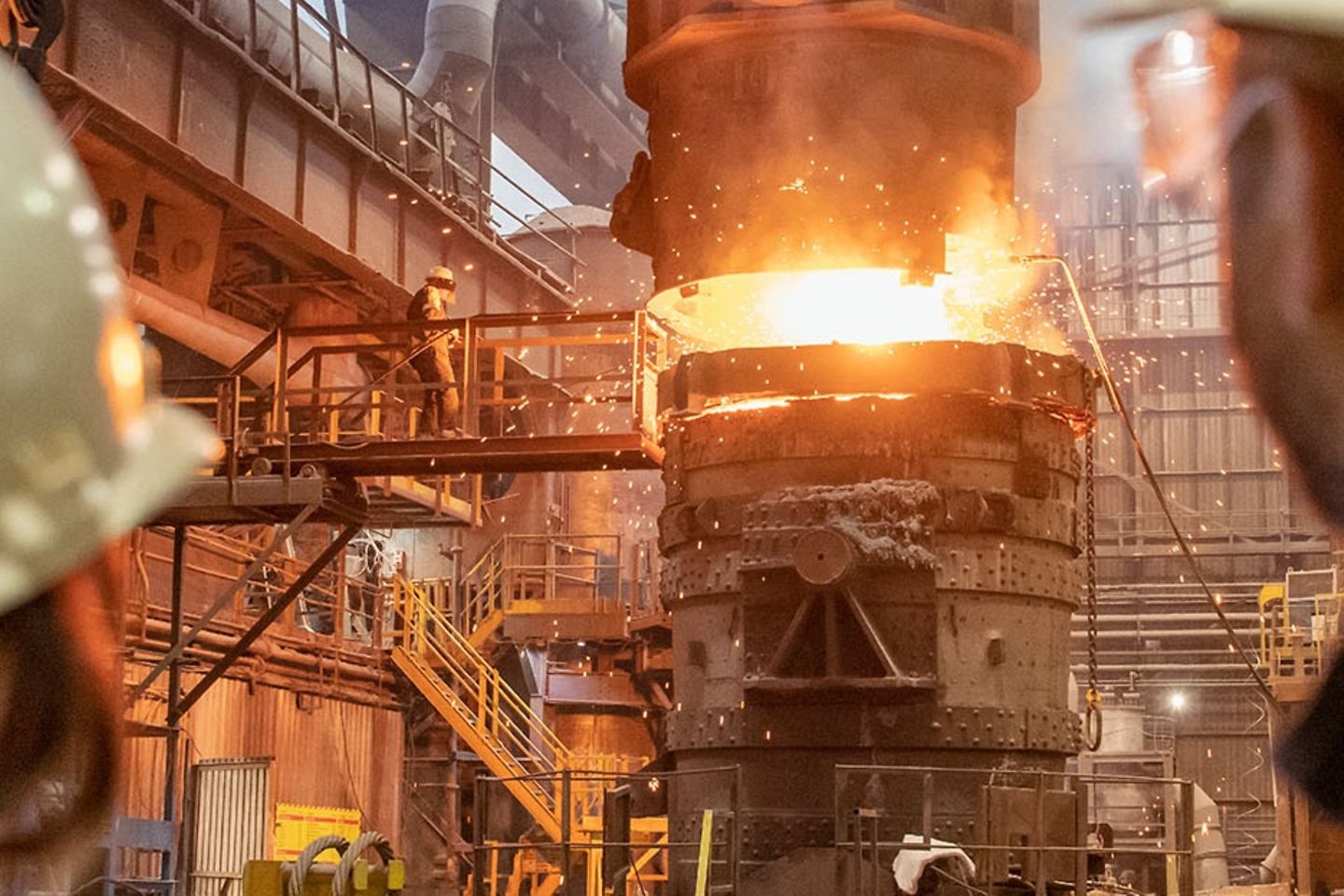 A female and a male steelworker look at a foundry plant.