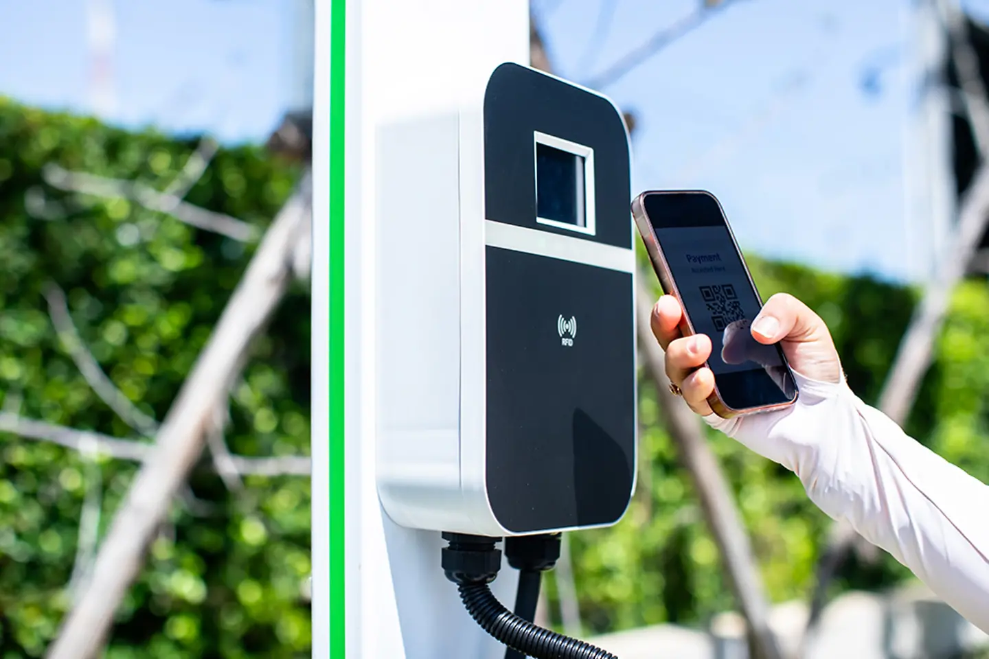 Fahrer eines Elektrofahrzeugs scannt QR-Code mit Smartphone