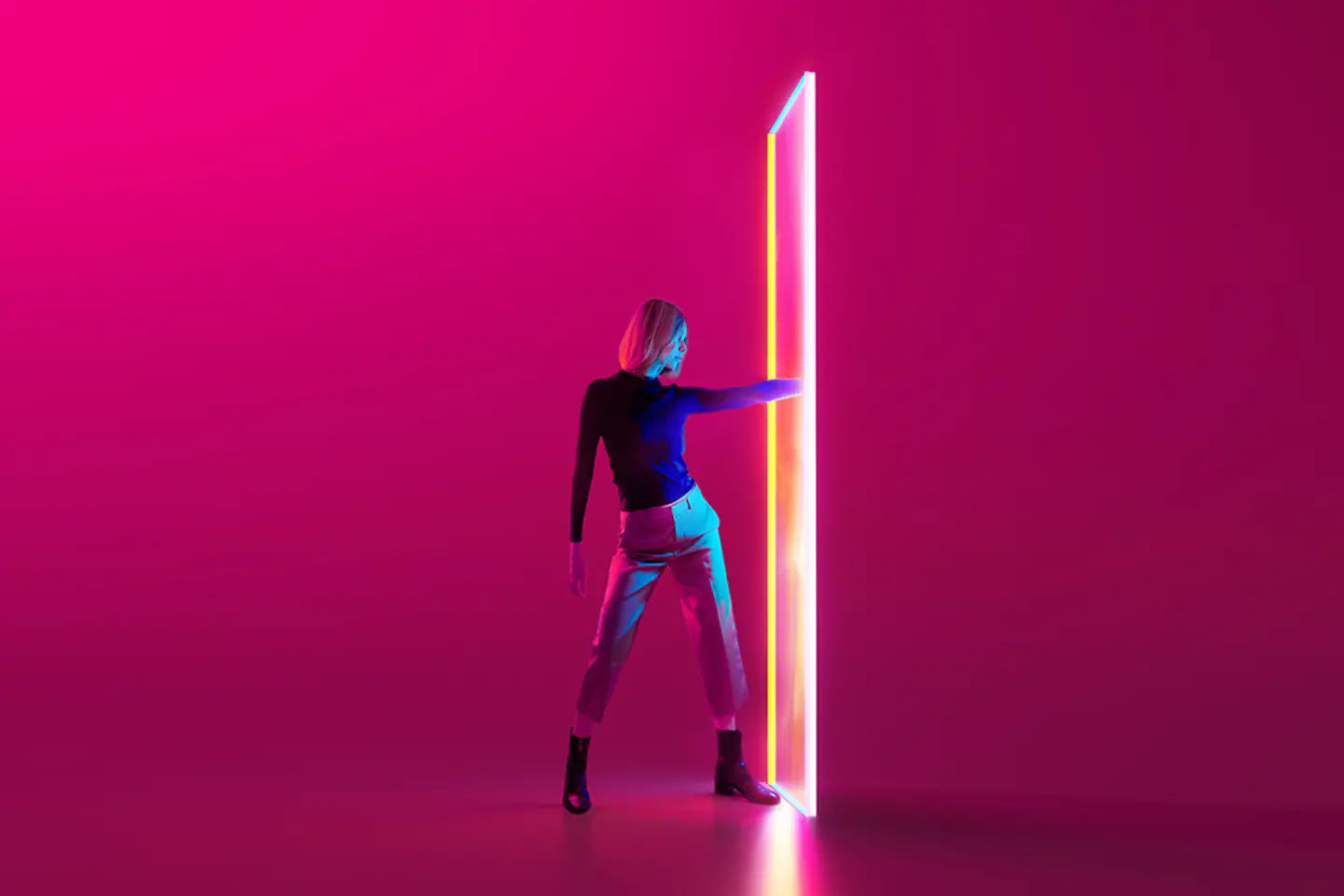 Image générée numériquement d’une jeune femme sur fond rouge, qui passe une main à travers un portail coloré et lumineux.