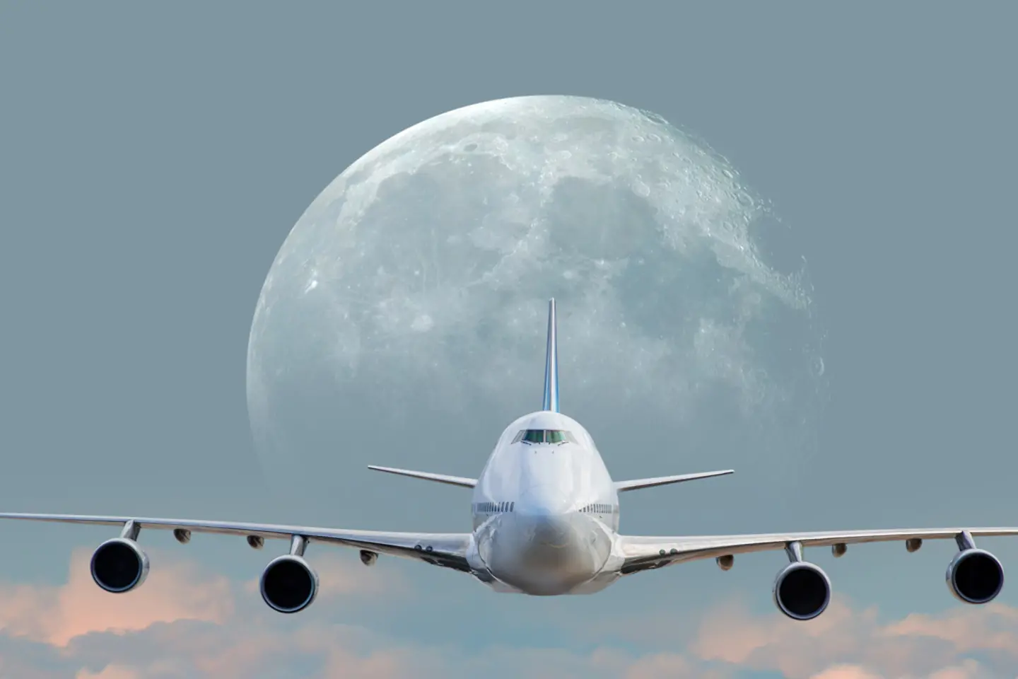 Un avion de ligne blanc au-dessus des nuages par pleine lune