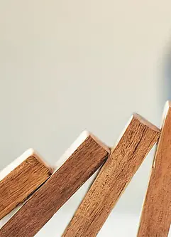 Eine Hand verhindert, dass Holzdominos umfallen, was symbolisch für die Verhinderung einer Unternehmenskrise steht