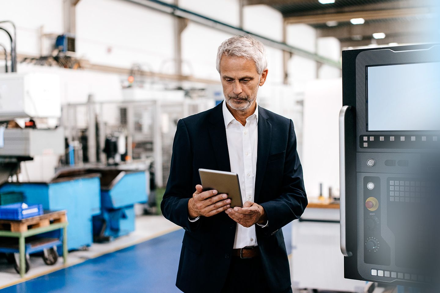 Production manager in production hall looks at a tablet