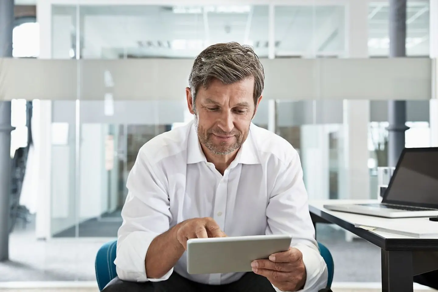 Geschäftsmann liest Neue Impulse Newsletter am Tablet.