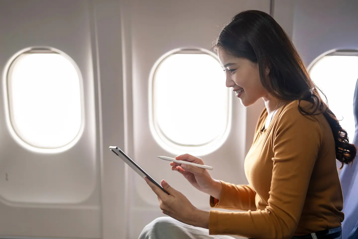 Junge Geschäftsfrau bei der Arbeit am Tablet in einem Flugzeug