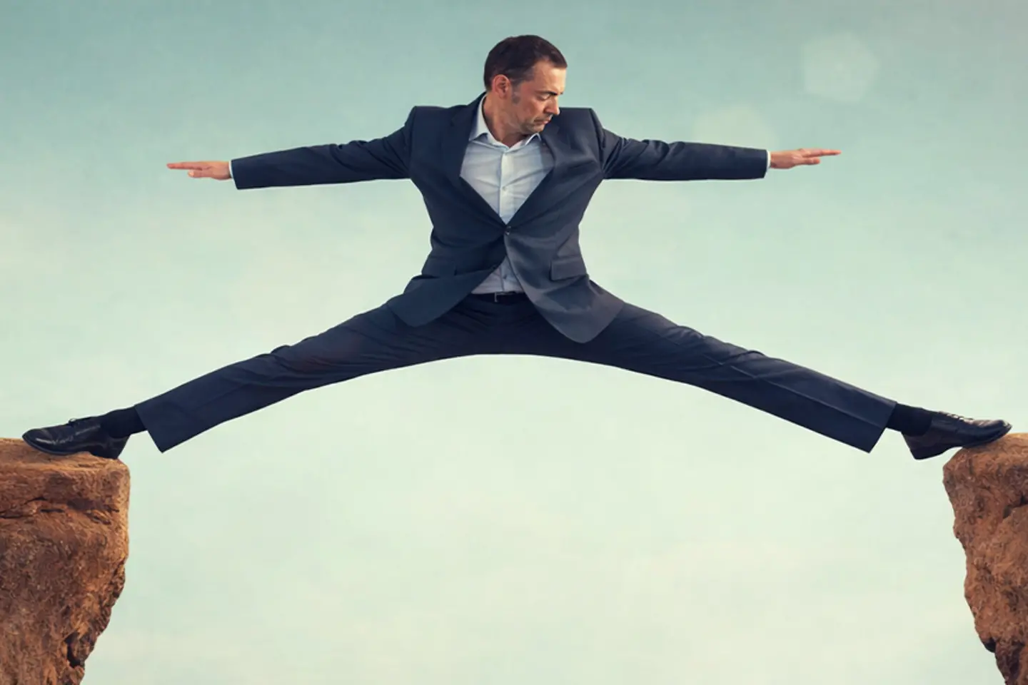 AI-generated image - A businessman is doing the splits from one mountaintop to another.
