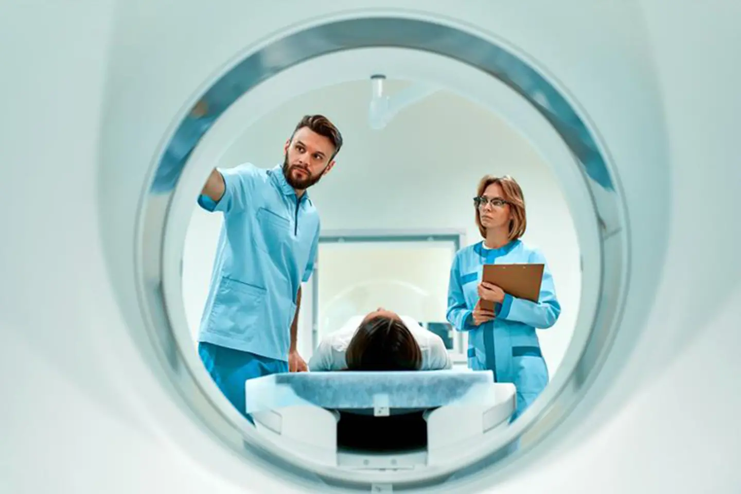 Dos médicos supervisando a un paciente entrando en un escáner de TC.