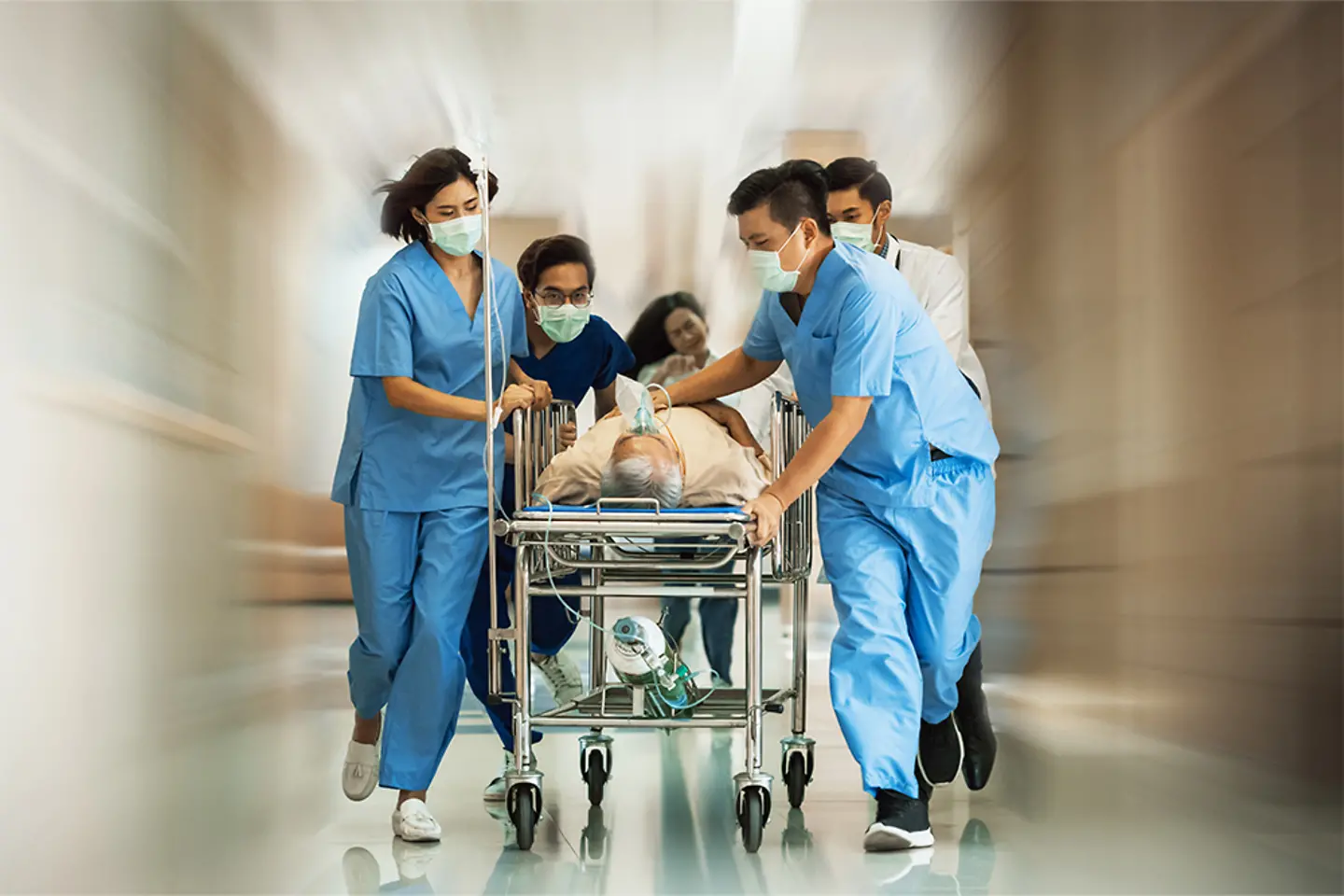 Un equipo de médicos corriendo con un paciente en una camilla con ruedas por la sala de urgencias