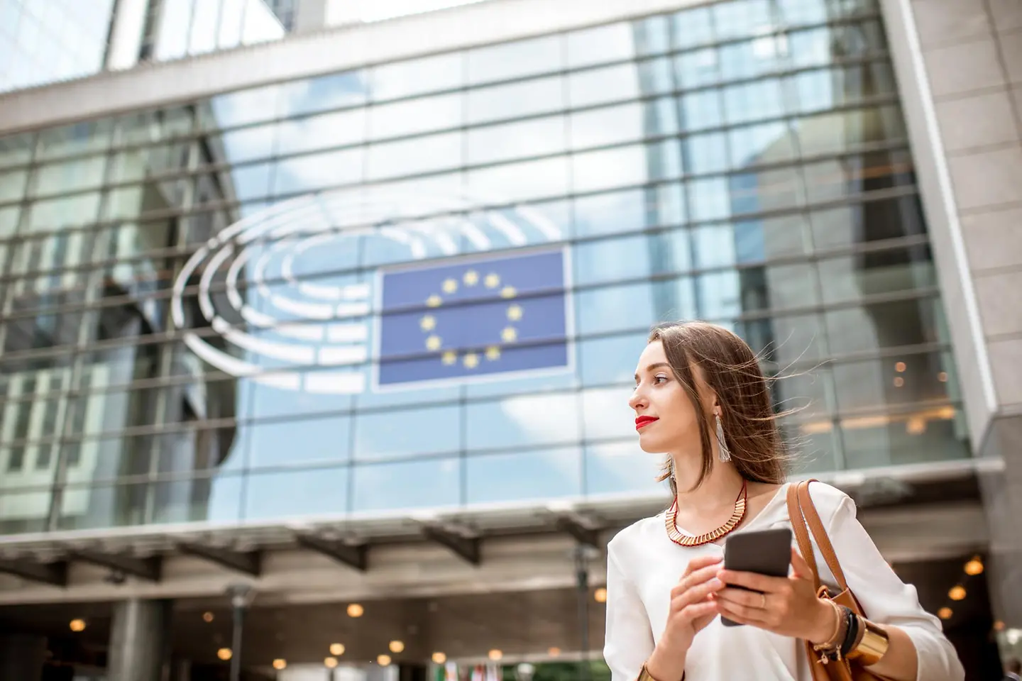 Young businesswoman standing with smartphone near parliament building European union Brussel