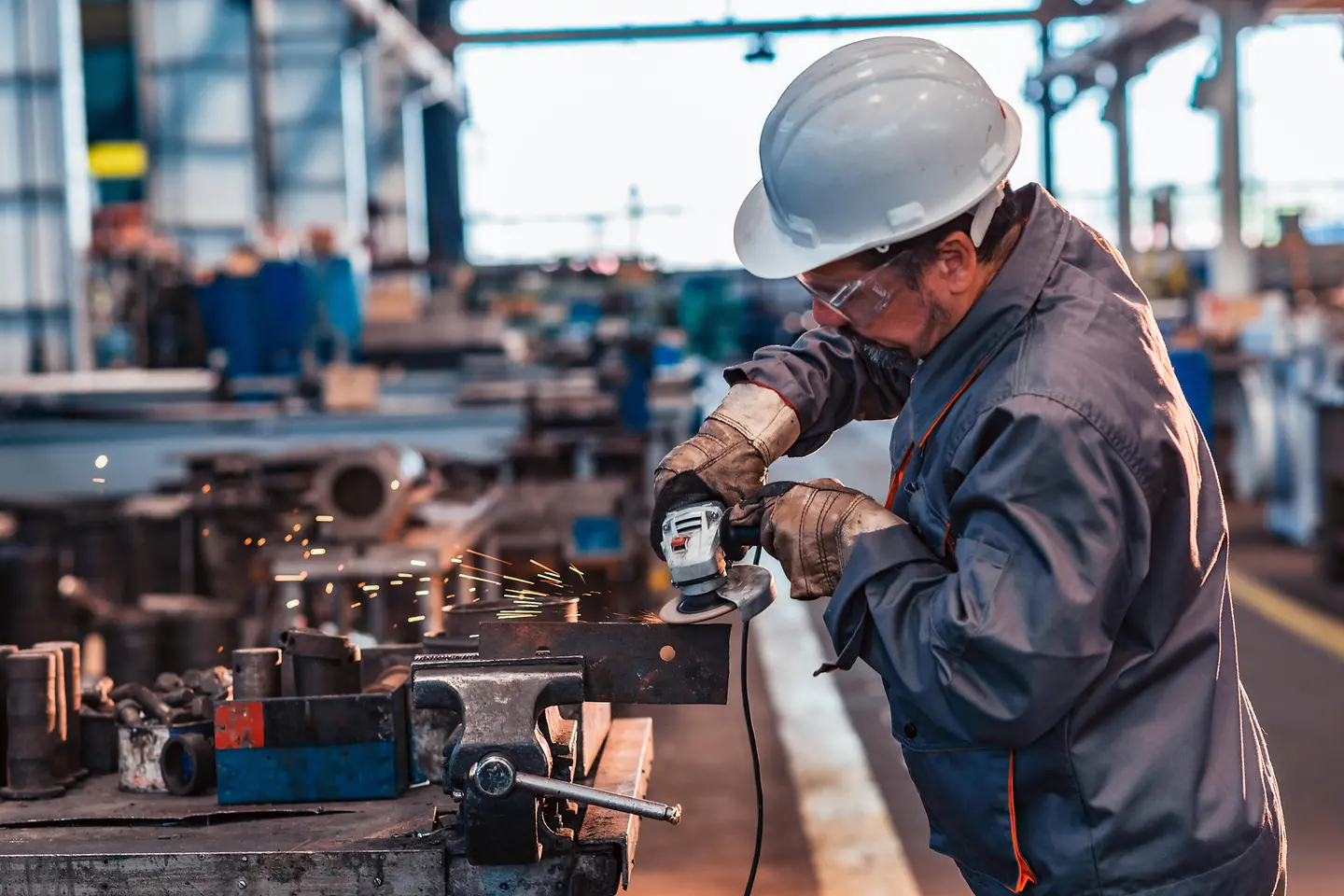 Skilled industrial worker grinding metal part